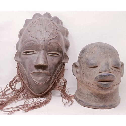 1121 - An African pottery mask, 24 cm high, and an African carved wooden mask, 32 cm (2)...