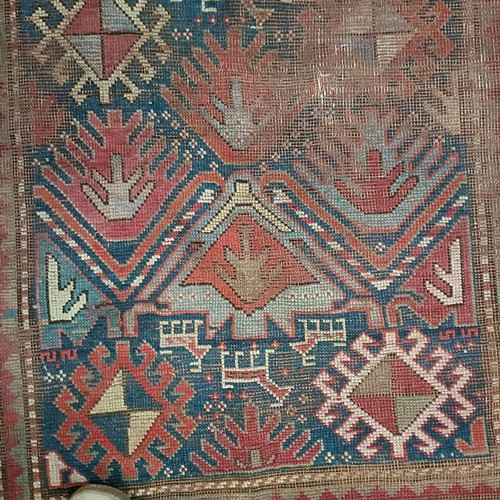 1303 - A Caucasian red ground rug, 216 x 125 cm