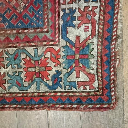 1303 - A Caucasian red ground rug, 216 x 125 cm