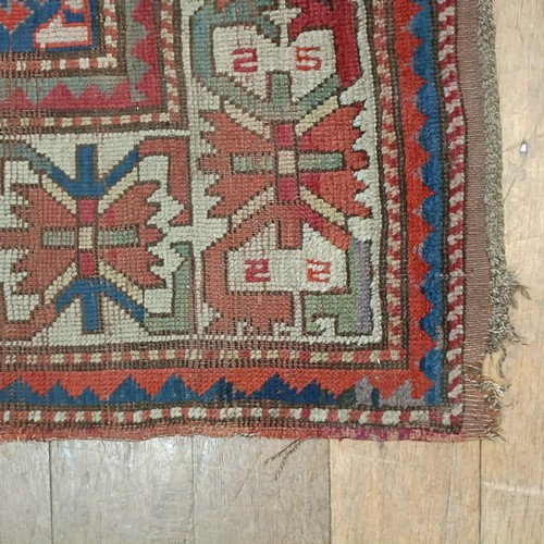 1303 - A Caucasian red ground rug, 216 x 125 cm