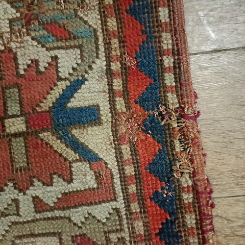 1303 - A Caucasian red ground rug, 216 x 125 cm