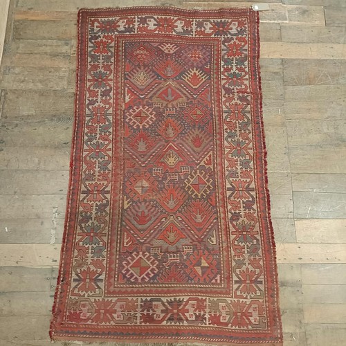 1303 - A Caucasian red ground rug, 216 x 125 cm