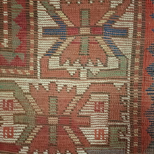 1303 - A Caucasian red ground rug, 216 x 125 cm