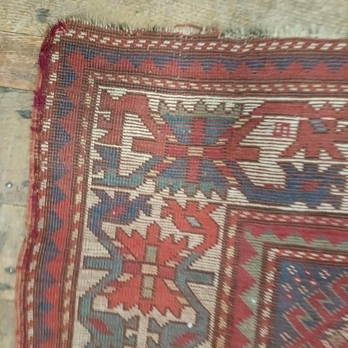 1303 - A Caucasian red ground rug, 216 x 125 cm