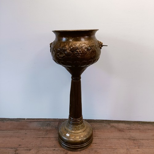 1302 - An embossed brass jardinière, on stand, 107 cm high