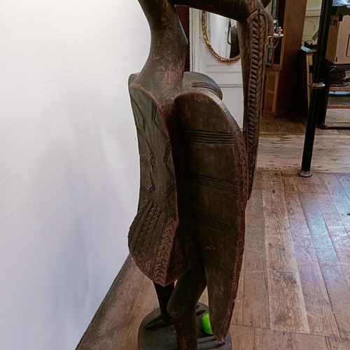 1306 - A large African carved wooden figure of a bird, 152 cm high