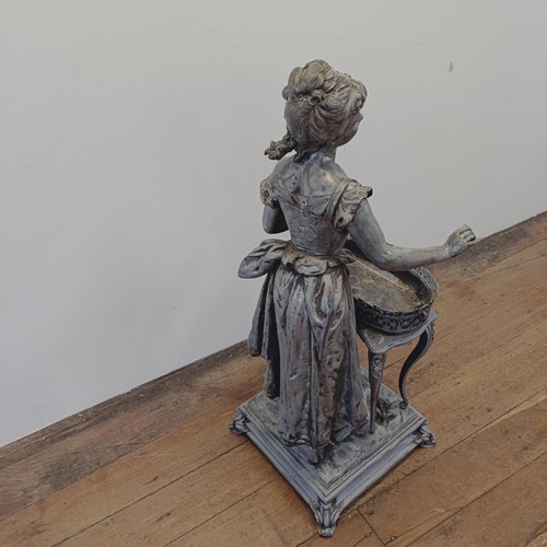 1298 - A large spelter figure of a lady in front of a table, on a square base, 100 cm high