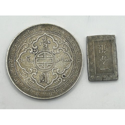 307 - A trade dollar, 1909, and a small Chinese silver coloured ingot (2)...