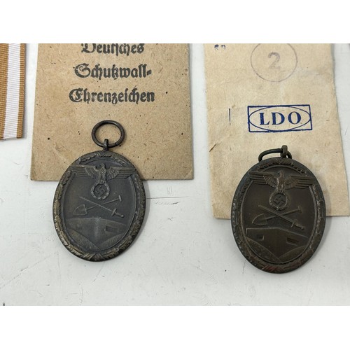 555 - A German World War II West Wall medal, with a packet, another similar and two German War Merit medal... 