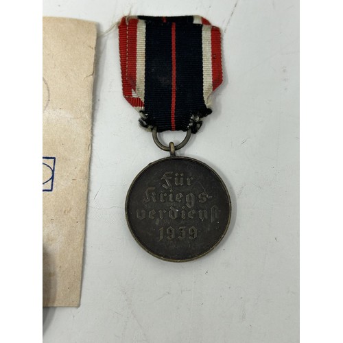 555 - A German World War II West Wall medal, with a packet, another similar and two German War Merit medal... 