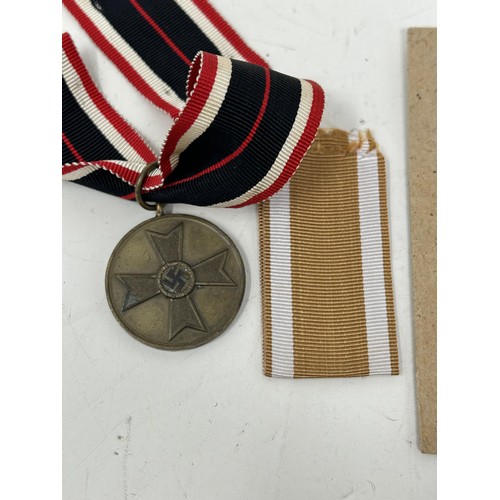 555 - A German World War II West Wall medal, with a packet, another similar and two German War Merit medal... 