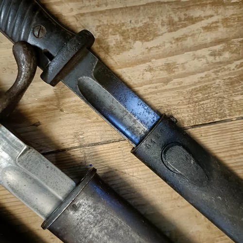 500 - A 1907 pattern bayonet, in a leather scabbard, and two other bayonets with scabbards (3)