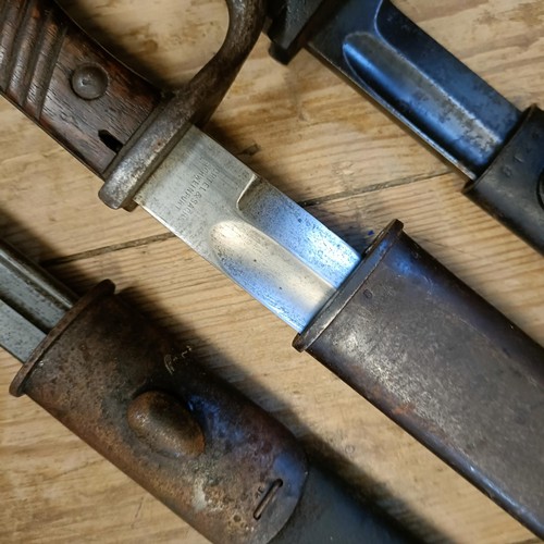 500 - A 1907 pattern bayonet, in a leather scabbard, and two other bayonets with scabbards (3)