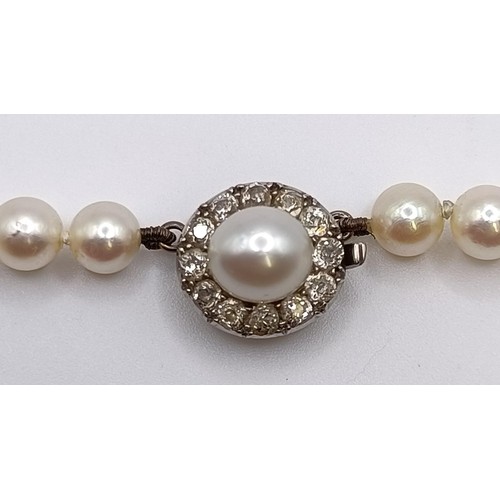 1605 - A cultured pearl necklace, with a diamond clasp, in a vintage jewellery box