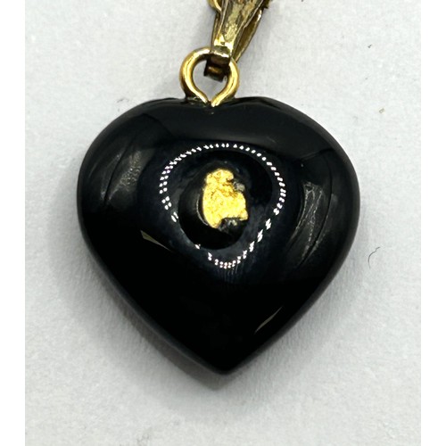 1760 - A yellow metal brooch, and a black stone and yellow metal heart shaped pendant, on a chain (2)