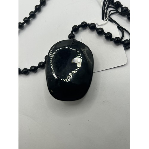 1649 - A carved obsidian pendant, on a bead chain