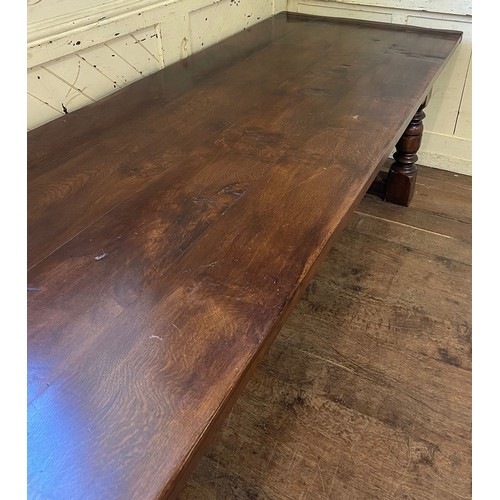 1259 - A large 18th century style oak refectory dining table, with turned legs, united by a stretcher, the ... 