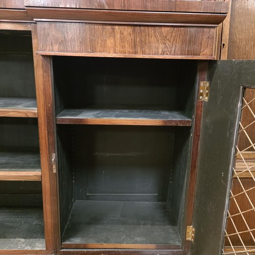 1274 - A late Regency rosewood inverted breakfront bookcase, with a mirrored superstructure raised on metal... 