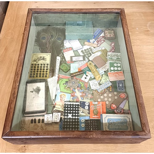 27 - Assorted sewing items, in a display box, and a framed group of early 20th century advertisements (2)... 