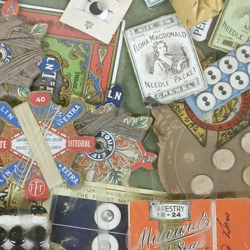 27 - Assorted sewing items, in a display box, and a framed group of early 20th century advertisements (2)... 