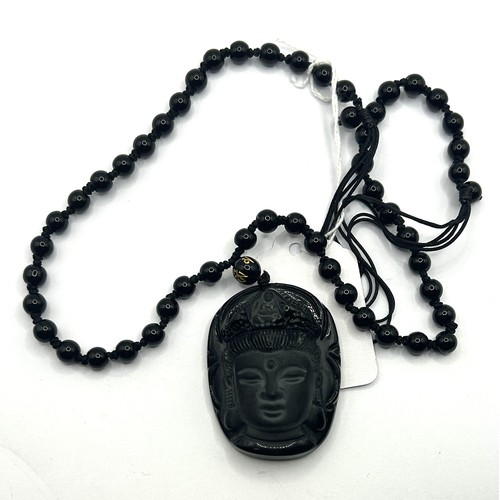 650 - A silver coloured metal bangle, and a carved obsidian pendant, on a bead chain (2)