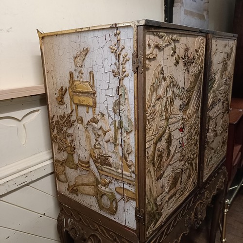 688 - A Chinese style drinks cabinet, the sides inset with plaster relief decorated landscapes, with two d... 