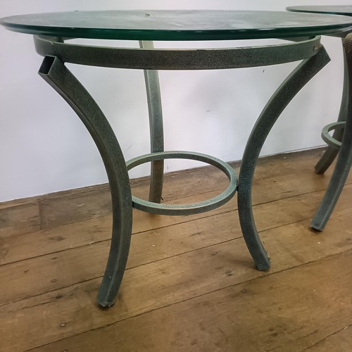 716 - A pair of glass top side tables, on metal bases, 60 cm diameter (2)