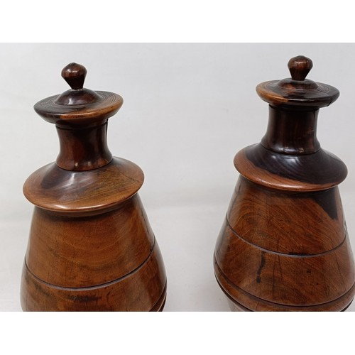 610 - A pair of turned lignum vitae urns and cover, 30 cm high (2)