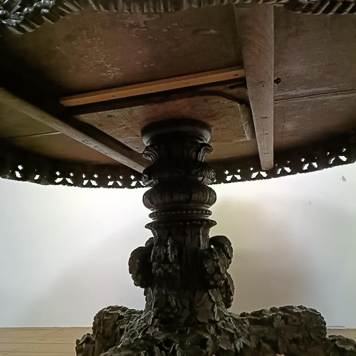 755 - A carved Burmese centre table, with a carved and pierced frieze, to a column support to a triangular... 