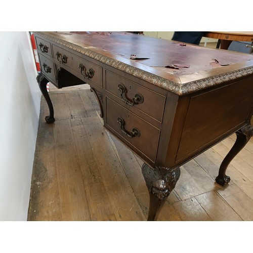 773 - A mahogany kneehole desk, having five drawers, flanked by faux drawers, on carved cabriole legs, and... 