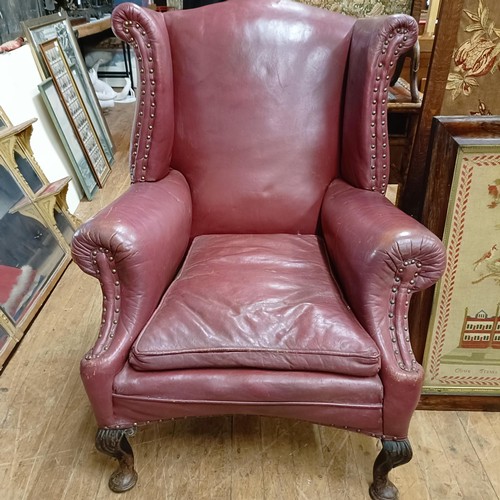 812 - A George III style leather wingback armchair, on carved cabriole legs to pad feet