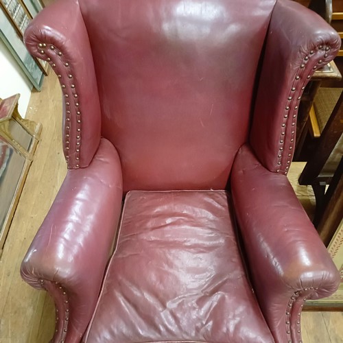 812 - A George III style leather wingback armchair, on carved cabriole legs to pad feet