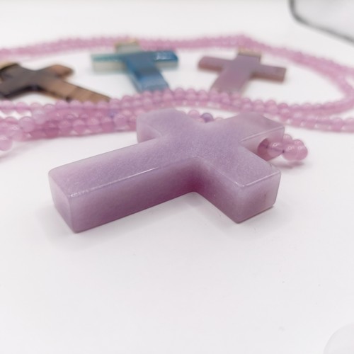 605 - A carved pink stone cross pendant, on a beaded necklace, and three carved hardstone crosses, with gi... 