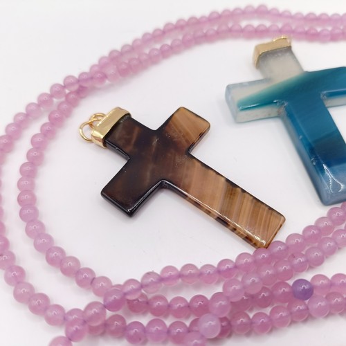 605 - A carved pink stone cross pendant, on a beaded necklace, and three carved hardstone crosses, with gi... 