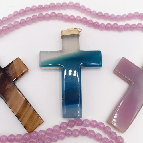 605 - A carved pink stone cross pendant, on a beaded necklace, and three carved hardstone crosses, with gi... 