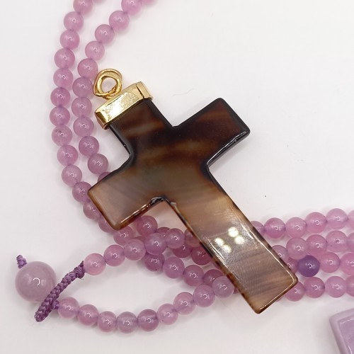 605 - A carved pink stone cross pendant, on a beaded necklace, and three carved hardstone crosses, with gi... 