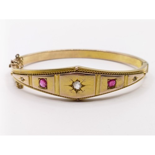 688 - A late 19th century yellow coloured metal, ruby and diamond bangle