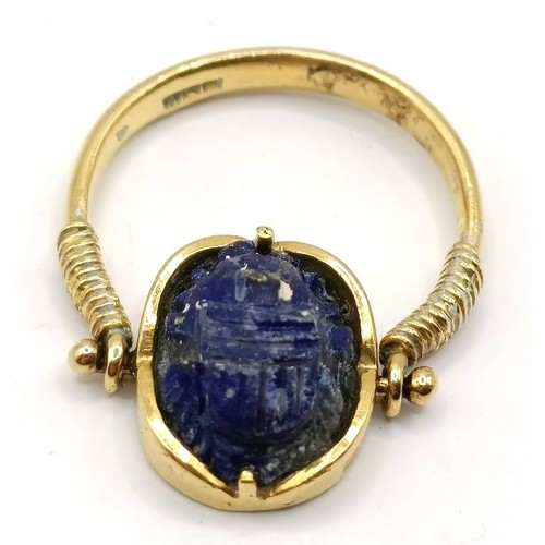 711 - A gold and carved blue stone Egyptian style ring, blue stone carved in the form of a scarab, ring si... 