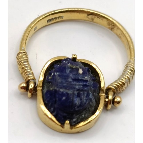 711 - A gold and carved blue stone Egyptian style ring, blue stone carved in the form of a scarab, ring si... 