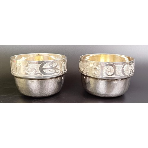 137 - A pair of silver tumblers, engraved names to the borders and with hammered decoration, Malcolm Apple... 