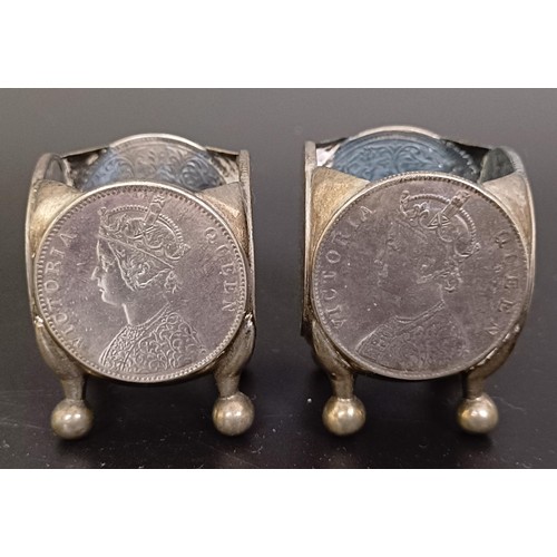 170 - A pair of silver coloured metal salts, inset with four coins, a pair of silver plated bottle coaster... 