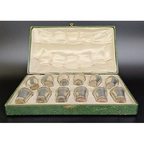 141 - A set of twelve Continental silver coloured metal shot cups, 107 g, cased