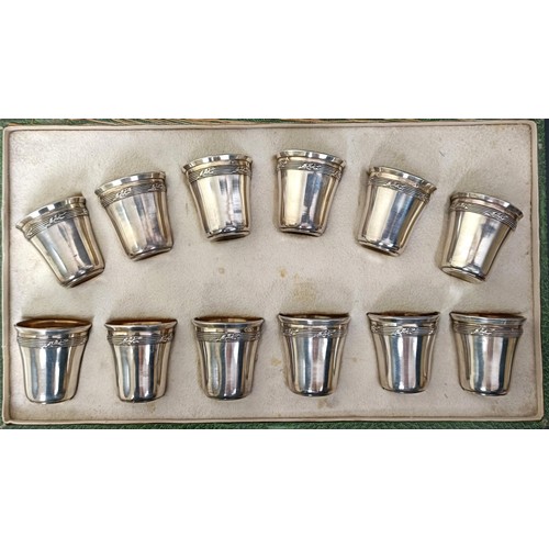 141 - A set of twelve Continental silver coloured metal shot cups, 107 g, cased