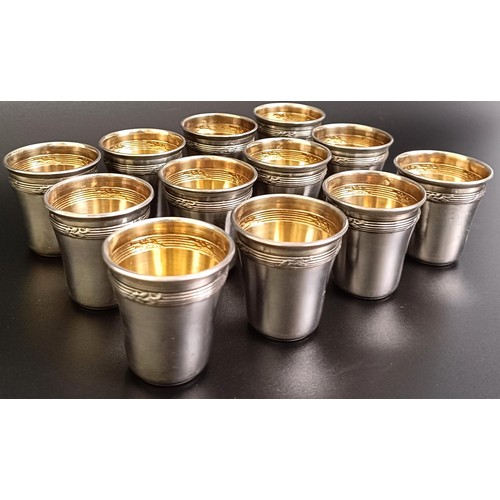 141 - A set of twelve Continental silver coloured metal shot cups, 107 g, cased