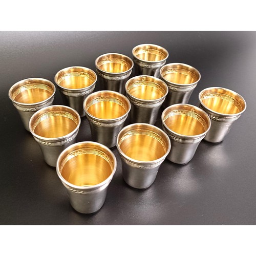 141 - A set of twelve Continental silver coloured metal shot cups, 107 g, cased