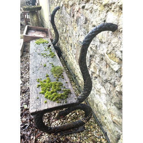 1356 - A garden bench, with cast iron ends in the form of snakes, 133 cm wide, seat heavily weathered, lack... 