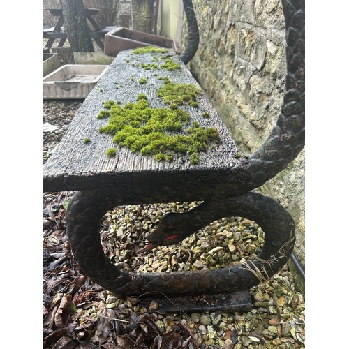 1356 - A garden bench, with cast iron ends in the form of snakes, 133 cm wide, seat heavily weathered, lack... 