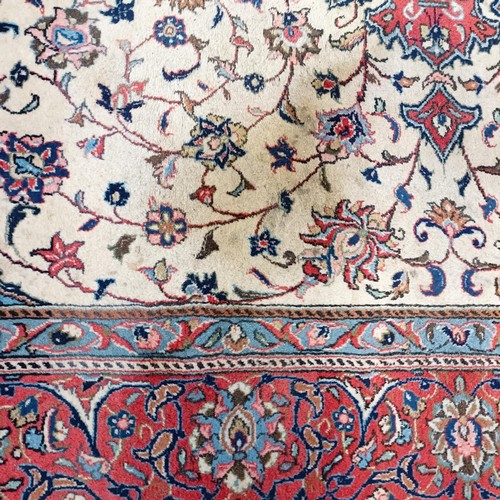 1350 - A Persian cream ground carpet, centre with repeating foliate forms and a main red border, 310 x 200 ... 