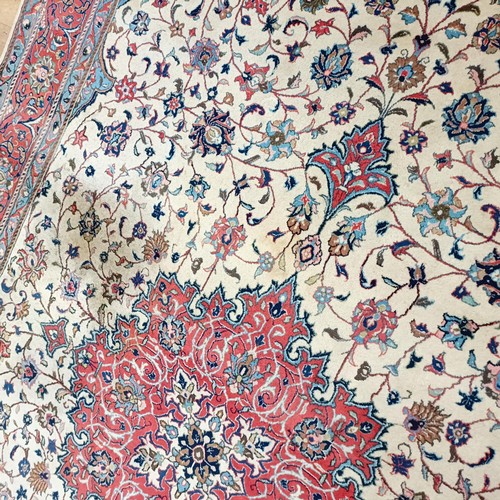 1350 - A Persian cream ground carpet, centre with repeating foliate forms and a main red border, 310 x 200 ... 