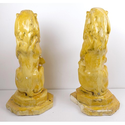 1115 - A pair of yellow glazed lion finials, various losses, 63 cm high (2)